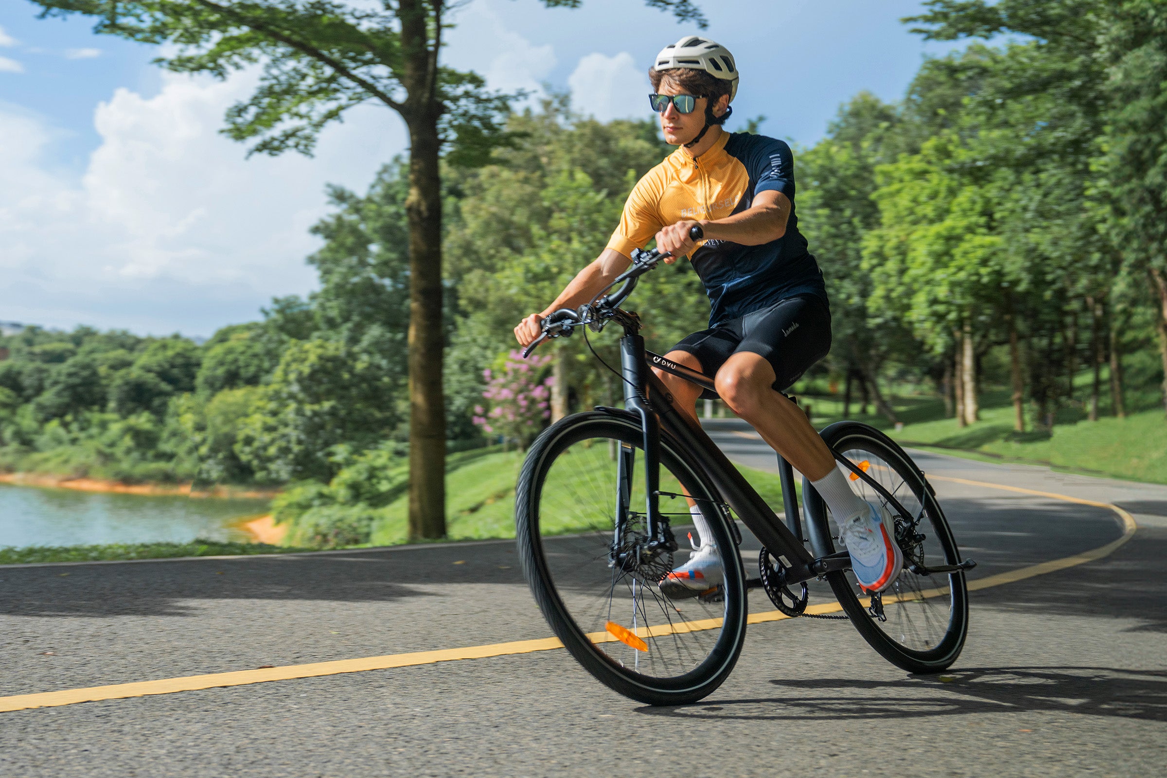 Cyclist in orange and blue outfit riding DYU Stroll 1 electric bike on scenic path. Cyclist in orange and blue outfit riding DYU Stroll 1 electric bike on scenic path.