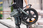 A man is carrying a folded DYU T1 20 Inch Foldable Electric Bike while climbing stairs