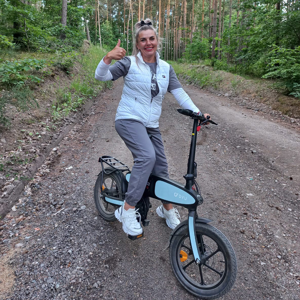 Woman is riding an electric bicycle on a dirt road.