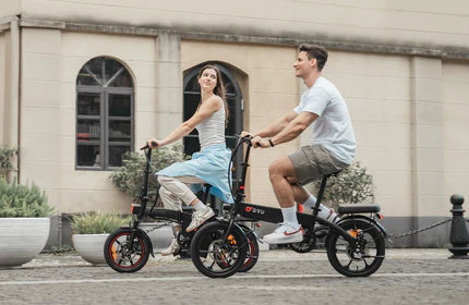 A man and a woman are riding electric bicycles side by side on a city street.