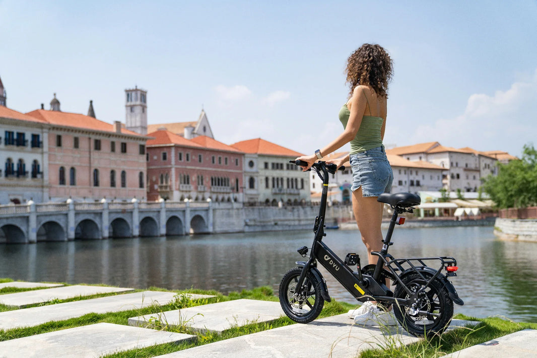 DYU C3 budget folding e-bike riding beside a city waterfront in the UK
