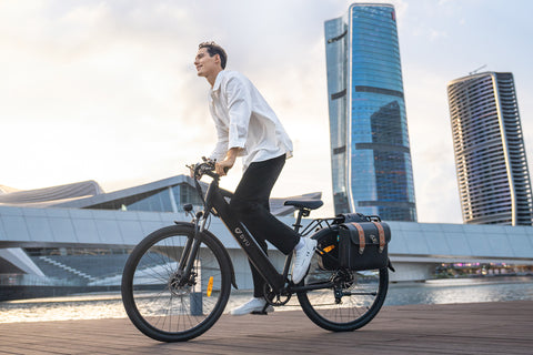 Person riding matte black DYU C5 electric bike near modern cityscape.