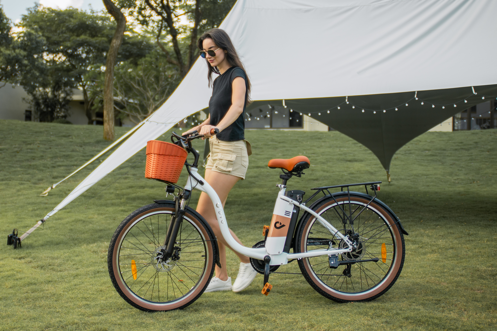 Woman beside white DYU C6 Pro electric bike with orange basket, ideal for outdoor commuting.