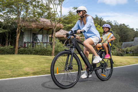 Woman riding matte black DYU C5 electric bike with child passenger on sunny road.